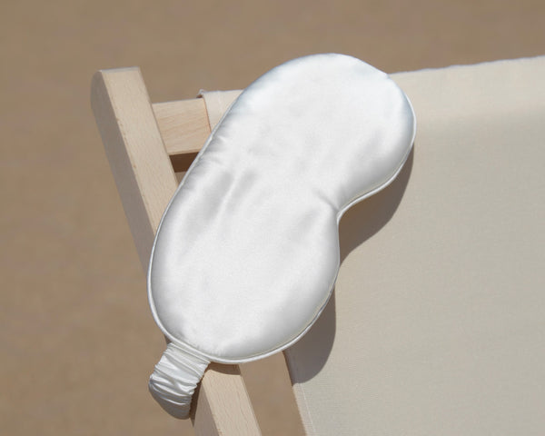 ivory silk eye mask draped across a deck chair 