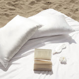Set of two white mulberry silk pillowcases on the beach with a pure silk eye mask.