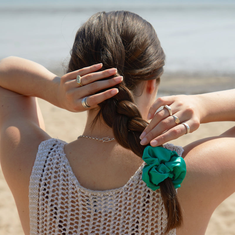 Lady wearing a large emerald green silk scrunchie in her hair.