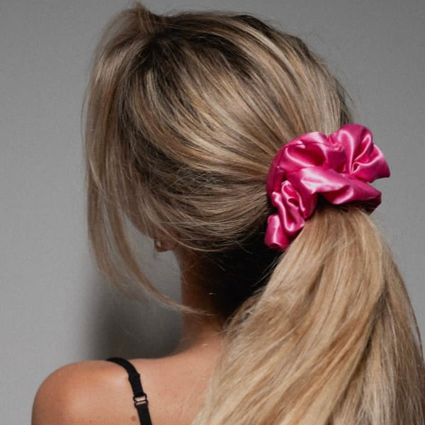 Lady wearing a large bright pink silk scrunchie in her long thick hair.